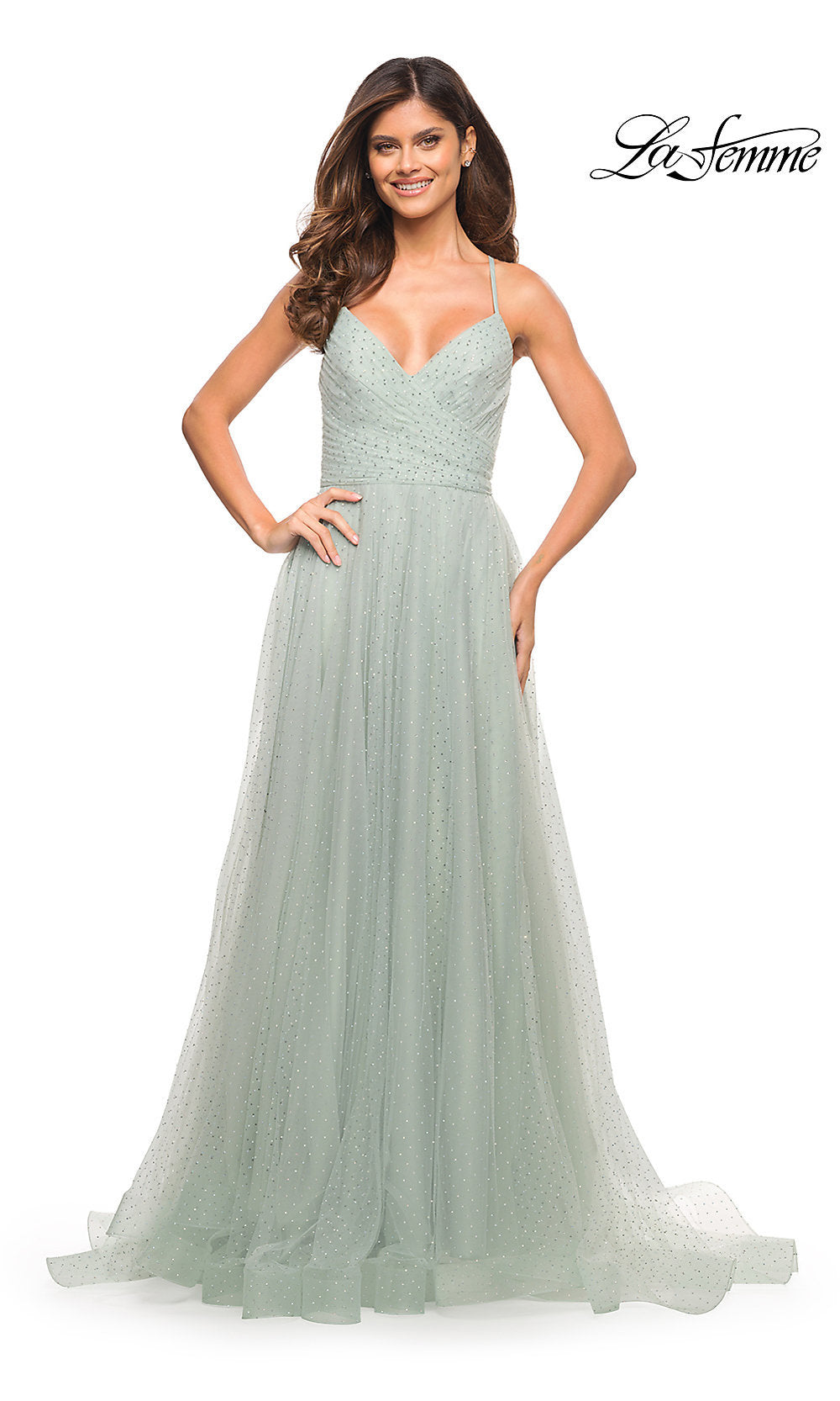 A woman wearing the La Femme Long Beaded Tulle Ball Gown for Prom, a light green floor-length dress with thin straps and a fitted bodice, stands against a white background.